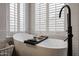 Relaxing bathtub showcasing a standalone tub beneath shuttered windows and a contemporary black faucet at 10423 E Verbena Ln, Scottsdale, AZ 85255