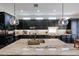A stylish kitchen features dark cabinets, a granite island with sink, stainless steel appliances, and modern pendant lighting at 10423 E Verbena Ln, Scottsdale, AZ 85255