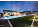 Illuminated backyard pool with artificial turf, desert landscaping, and mountain views at twilight at 10423 E Verbena Ln, Scottsdale, AZ 85255