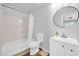 Clean bathroom with tub and shower, white vanity with sink and round mirror at 14521 W Gelding Dr, Surprise, AZ 85379
