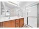 Bathroom featuring double sinks, wood cabinets, and a glass enclosed shower at 14521 W Gelding Dr, Surprise, AZ 85379
