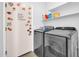 Well-lit laundry room with modern washer and dryer, cute door decorations, and shelving at 14521 W Gelding Dr, Surprise, AZ 85379