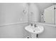 Bright powder room with pedestal sink, decorative mirror, and updated fixtures at 14521 W Gelding Dr, Surprise, AZ 85379