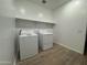 A functional laundry room with appliances, convenient shelving and tile floors at 15777 W Cheryl Dr, Waddell, AZ 85355