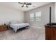 Neutral bedroom featuring carpet, ceiling fan, tv, and natural light from two windows at 16064 W Montana De Oro Dr, Surprise, AZ 85387