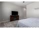 Comfortable bedroom with plush carpet, wall art, and a wooden entertainment center at 16064 W Montana De Oro Dr, Surprise, AZ 85387