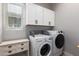 Functional laundry room with modern white appliances and storage cabinets at 16064 W Montana De Oro Dr, Surprise, AZ 85387