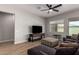 Bright living room with wood-look tile floors, ceiling fan, and a comfortable gray sectional sofa at 16064 W Montana De Oro Dr, Surprise, AZ 85387
