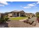 Manicured backyard with synthetic grass, stone landscaping, planters, and gravel at 16438 W Buchanan St, Goodyear, AZ 85338