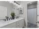Bathroom with dual sink vanity, quartz countertop, decorative mirror, and tub/shower combo at 16438 W Buchanan St, Goodyear, AZ 85338