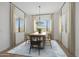 Bright dining room with a wooden table, modern chandelier, large windows, and a stylish blue area rug at 20373 W Rovey Ave, Buckeye, AZ 85396