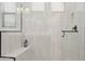 Modern shower with sleek white tiling, a built-in bench, and black hardware at 20373 W Rovey Ave, Buckeye, AZ 85396
