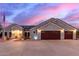 Charming home with a two-car garage, desert landscaping, and a welcoming entrance, illuminated by soft exterior lights at 23040 W Hammond Ln, Buckeye, AZ 85326