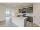 Modern kitchen with grey cabinets, stainless steel appliances, a kitchen island, and a view into the living room at 40030 W Bunker Dr, Maricopa, AZ 85138