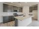 Spacious kitchen with grey cabinets, quartz countertops, stainless steel appliances, and large kitchen island at 40030 W Bunker Dr, Maricopa, AZ 85138