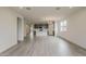 Open-concept living room with grey wood-look flooring, bright natural light, and modern chandelier at 40030 W Bunker Dr, Maricopa, AZ 85138