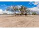 Sprawling property with a house framed by mature trees under a bright blue sky at 51089 W Julie Ln, Maricopa, AZ 85139
