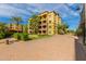 Exterior view of a tan apartment complex with palm trees and green landscape at 5450 E Deer Valley Dr # 3023, Phoenix, AZ 85054