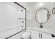 A bathroom features a tub with a shower, white vanity and round mirror at 6041 E Hartford Ave, Scottsdale, AZ 85254