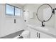 A modern bathroom featuring a glass-enclosed shower and a round mirror at 6041 E Hartford Ave, Scottsdale, AZ 85254