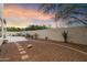 A spacious backyard featuring desert landscaping, a block wall and an extended patio under a colorful sunset sky at 8817 S 18Th Way, Phoenix, AZ 85042