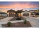 Charming home featuring desert landscaping, stone accents, and a three car garage at dusk at 8817 S 18Th Way, Phoenix, AZ 85042