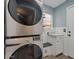 Well-lit laundry area with stacked washer and dryer, white cabinets, and window at 9509 W Tonopah Dr, Peoria, AZ 85382
