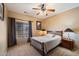 Cozy bedroom with a wood framed bed, ceiling fan, and a large window at 9722 W Prospector Dr, Queen Creek, AZ 85144