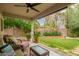 Relaxing covered patio with ceiling fan and wicker seating, overlooking a lush backyard at 9834 E Fairview Ave, Mesa, AZ 85208