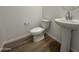 Powder room with pedestal sink, modern fixtures, and wood-look flooring at 15790 W Cheryl Dr, Waddell, AZ 85355