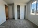 Bright bedroom with plush carpet, neutral walls, large window, and a sizable closet with sliding doors at 15790 W Cheryl Dr, Waddell, AZ 85355