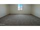 An empty bedroom featuring a window and soft, neutral-toned carpeting at 15790 W Cheryl Dr, Waddell, AZ 85355