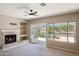Spacious living room with a fireplace, built in shelves, and sliding doors to backyard pool at 11451 E Christmas Cholla Dr, Scottsdale, AZ 85255