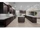 Large kitchen with dark wood cabinets, waterfall countertop island, and stainless appliances at 11977 N 81St St, Scottsdale, AZ 85260