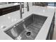 Close up of stainless steel kitchen sink and faucet, with white countertops and brown wood cabinets at 11977 N 81St St, Scottsdale, AZ 85260