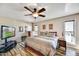 Cozy bedroom with wood-style flooring, ceiling fan, and ample natural light from large windows at 18410 N 104Th Ave, Sun City, AZ 85373
