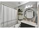 Cozy bathroom featuring modern fixtures, a shower with curtain, and a stylish round mirror above the sink at 18601 N 45Th Dr, Glendale, AZ 85308