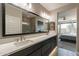 This bathroom includes a double vanity, large mirror, and walk-in shower with a door to the bedroom at 247 E Las Puertas Ln, Queen Creek, AZ 85140
