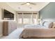 A neutral bedroom with a ceiling fan, large windows, and dresser with a TV at 247 E Las Puertas Ln, Queen Creek, AZ 85140