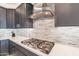 Close-up of the kitchen with stainless steel stove top, tile backsplash, and granite counters at 247 E Las Puertas Ln, Queen Creek, AZ 85140