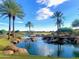 Picturesque pond with a small waterfall and verdant golf course and blue sky at 247 E Las Puertas Ln, Queen Creek, AZ 85140