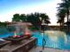 Outdoor community pool with a resort-style pool house, fire bowls, lush greenery, and beautiful palm trees at 247 E Las Puertas Ln, Queen Creek, AZ 85140