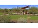 Community playground shaded by a canopy and surrounded by green grass and landscaping at 30406 N 116Th Ln, Peoria, AZ 85383