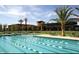 Community lap pool and clubhouse with lounge furniture surrounded by manicured landscaping at 30406 N 116Th Ln, Peoria, AZ 85383