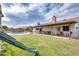 This backyard features a covered patio with seating, a pool, and grassy area with a play structure at 3149 W Danbury Dr, Phoenix, AZ 85053