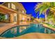 Relaxing backyard with pool, covered patio, lush landscaping, and illuminated palm trees at 3270 W White Canyon Rd, San Tan Valley, AZ 85144