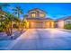 Charming two-story home with a three-car garage and palm trees, beautifully lit in the evening at 3270 W White Canyon Rd, San Tan Valley, AZ 85144