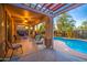 Relaxing covered patio overlooking a sparkling pool, complete with comfortable seating and serene views of the beautifully landscaped backyard at 3270 W White Canyon Rd, San Tan Valley, AZ 85144