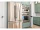 Modern kitchen with stainless steel refrigerator, built-in oven, and custom green cabinetry at 32771 N 70Th St, Scottsdale, AZ 85266