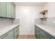 Well-organized laundry room with modern pale green cabinetry, marble countertops, and convenient floating shelves at 32771 N 70Th St, Scottsdale, AZ 85266